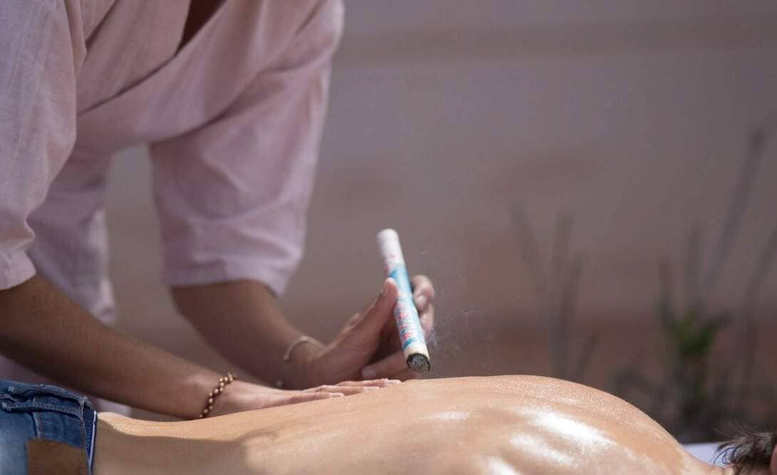 Una persona usando moxibustión en la espalda de otra persona
